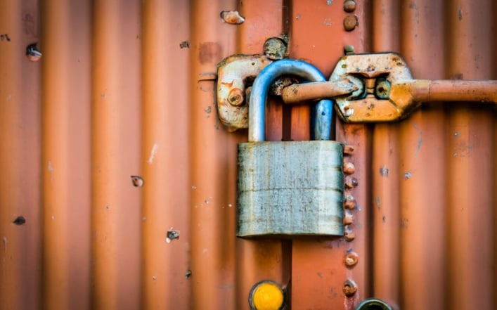 A worn metal container with a large padlock on the front.