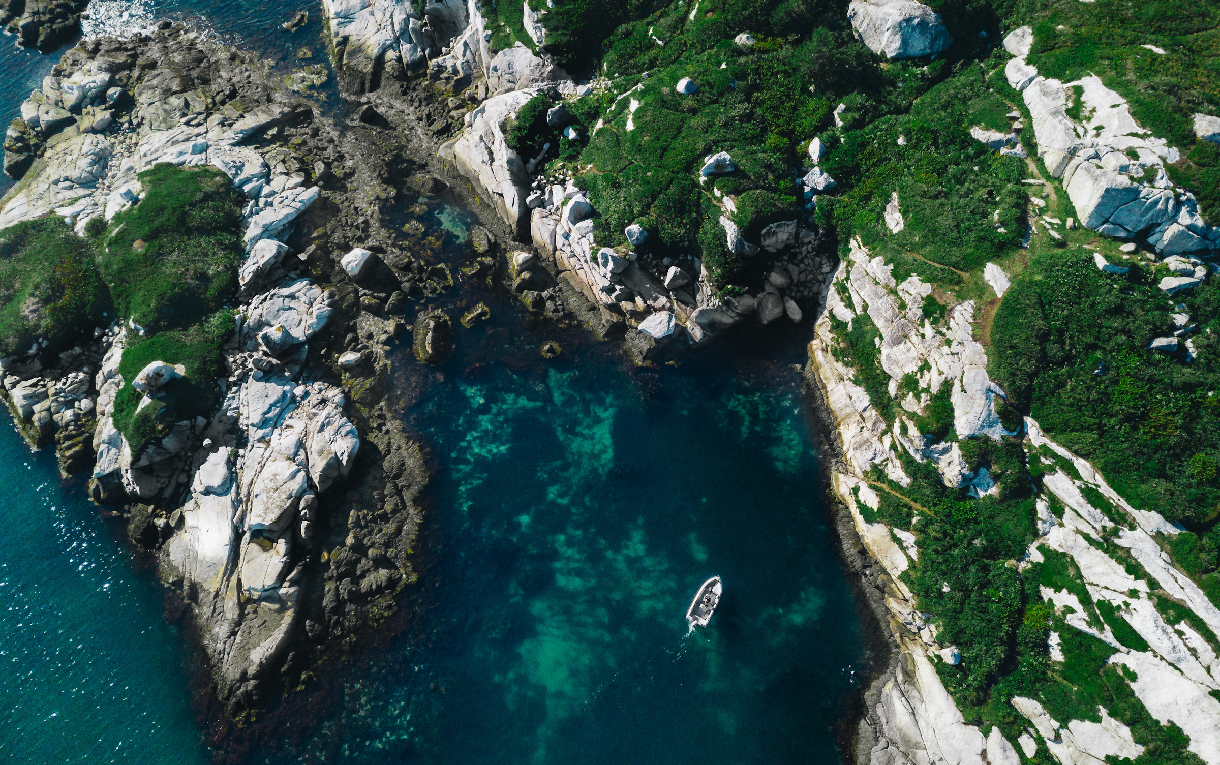 A small boat in a remote rocky cove.