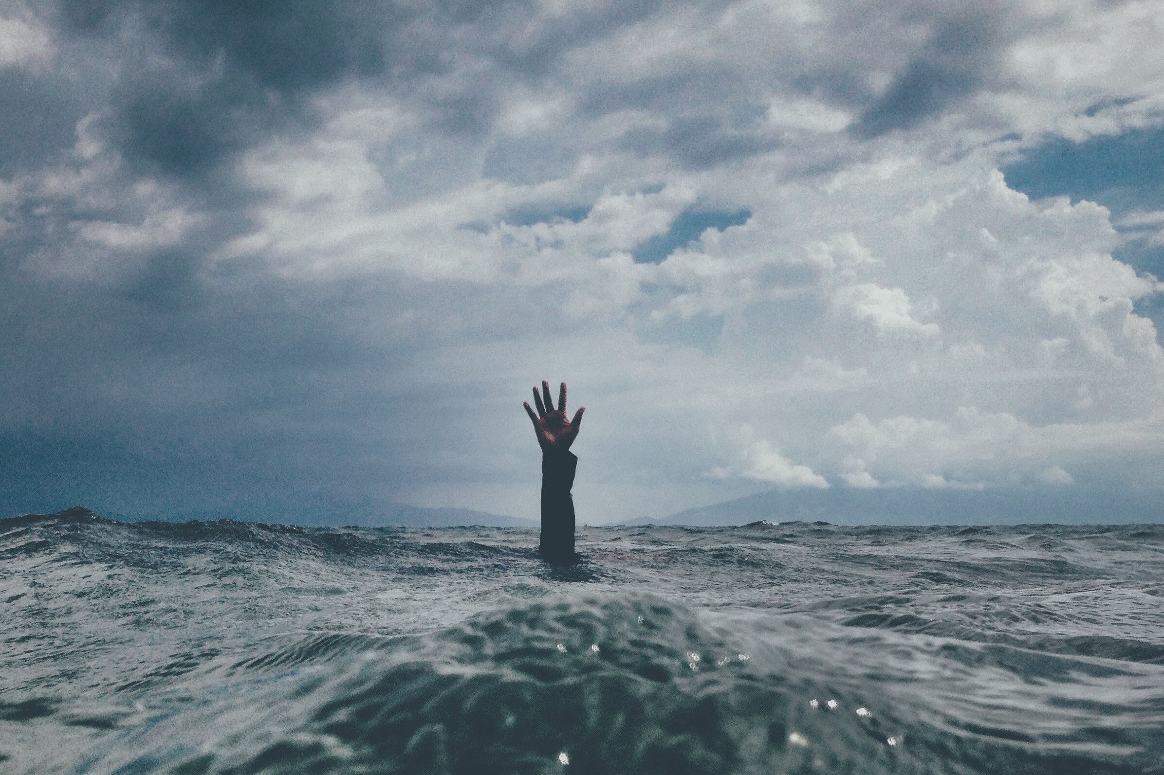 A photo of a sea with a hand rising from the water.