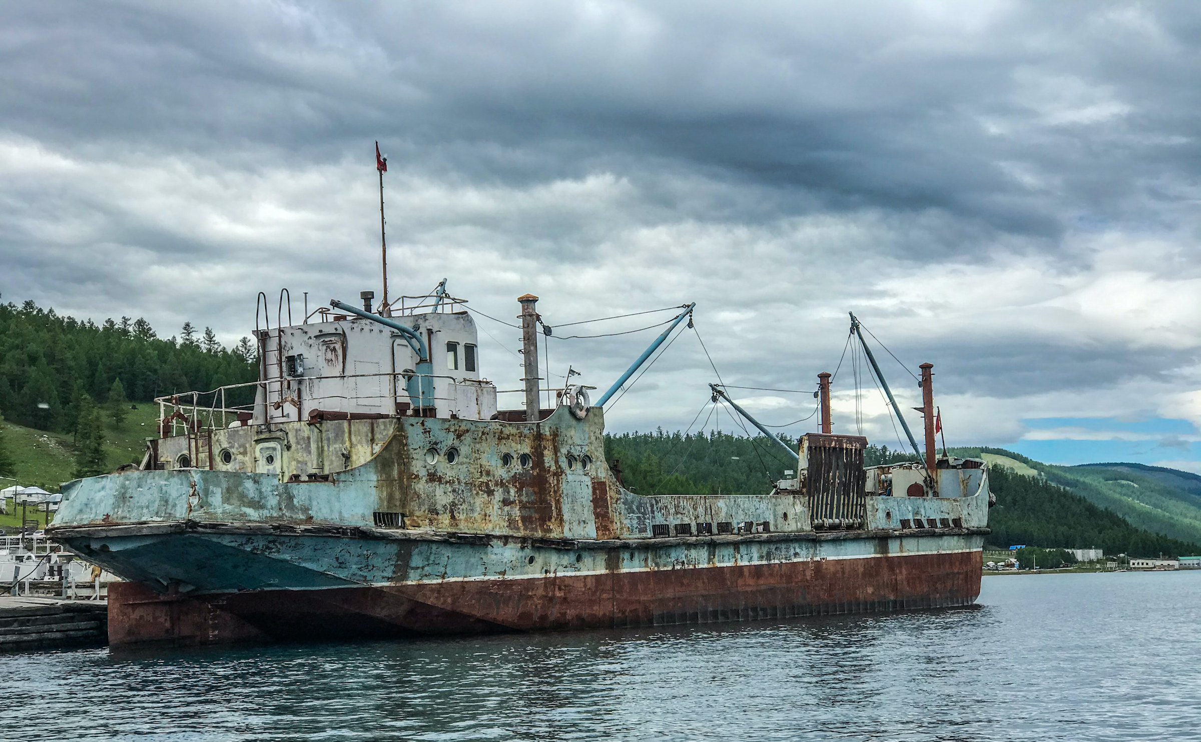 A poorly maintained and rusty fishing ship moored to a jetty.