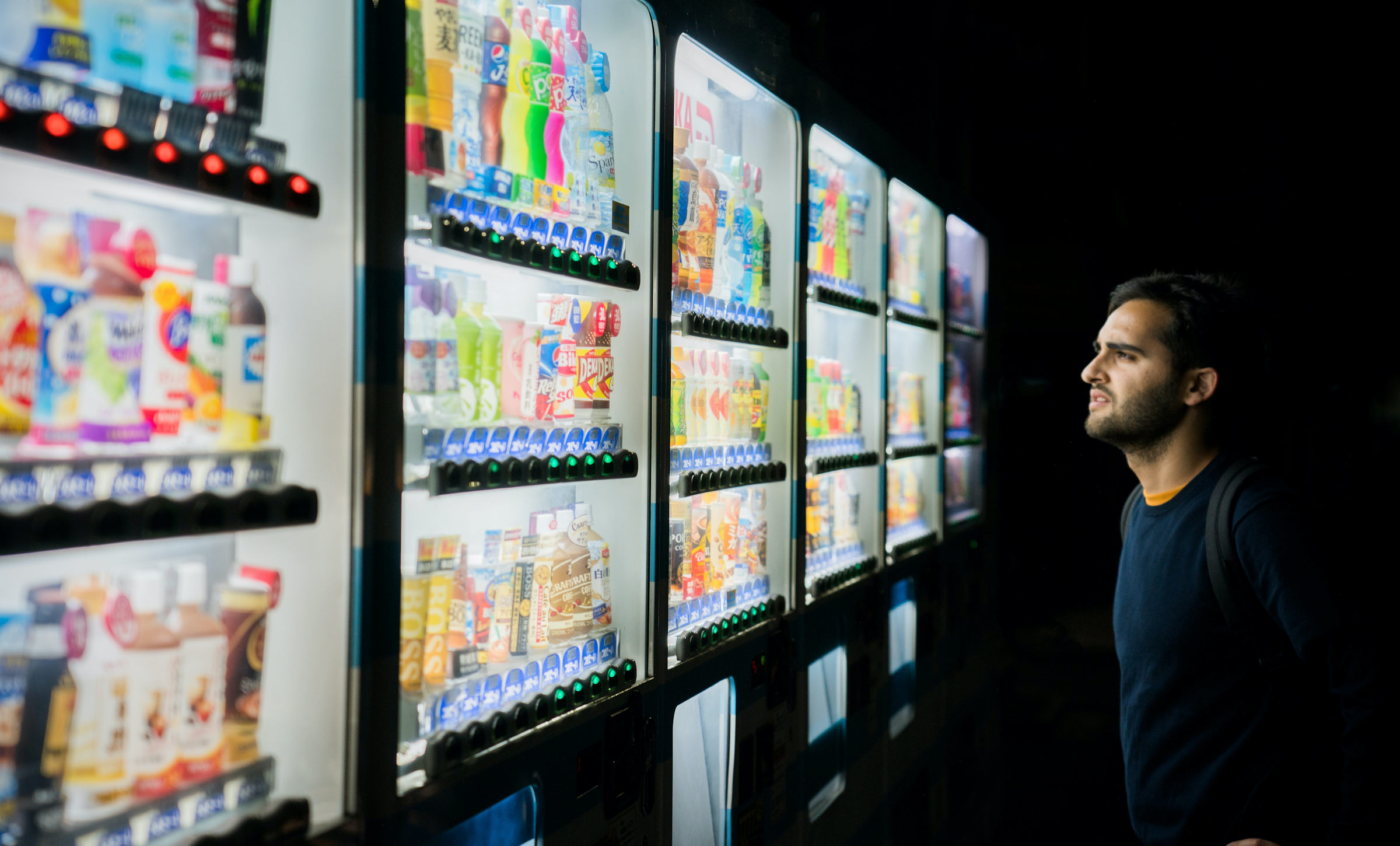Man looking at a row of vending machines.